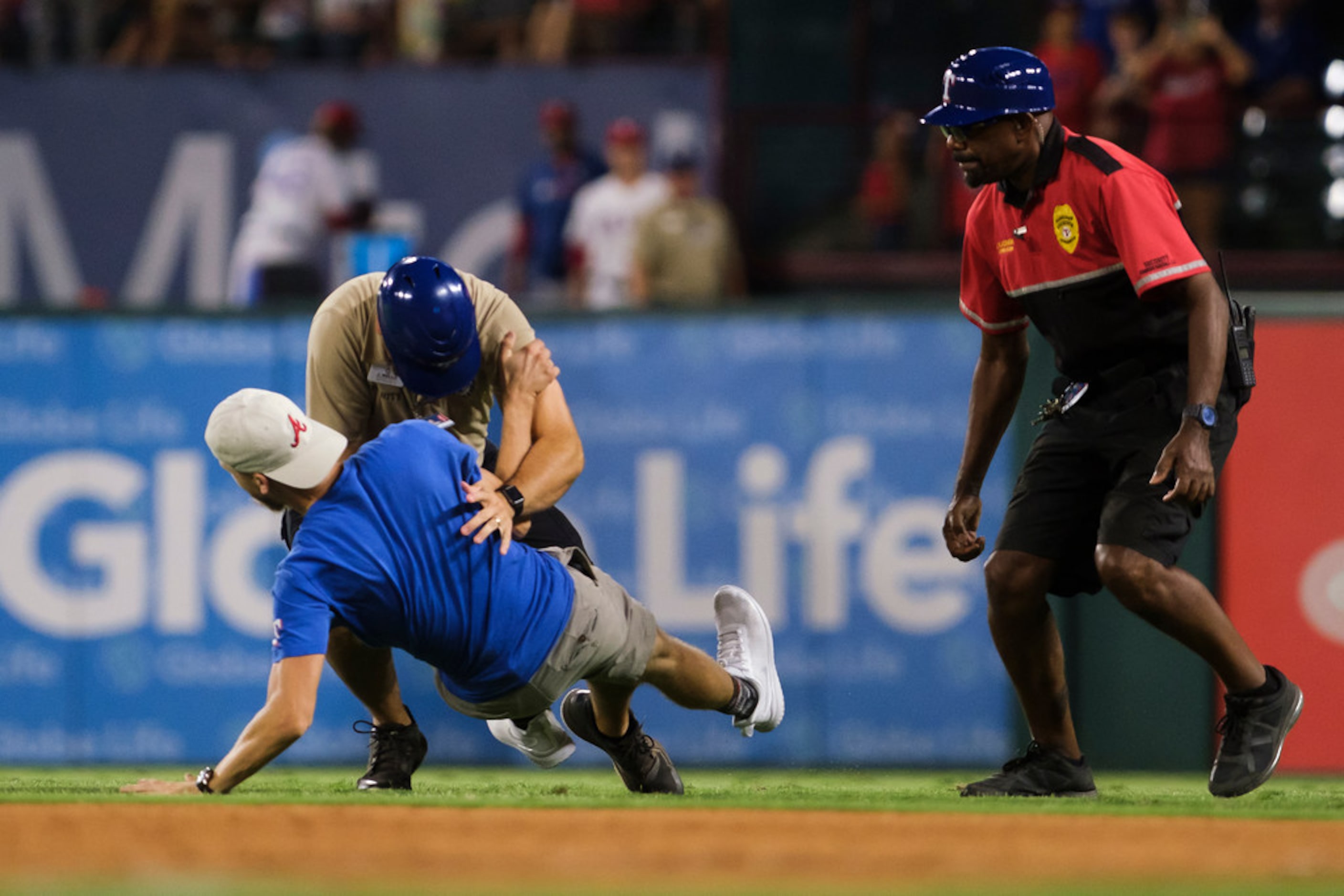 A security guard tackles a fan who ran on to the field during the ninth inning of a game...