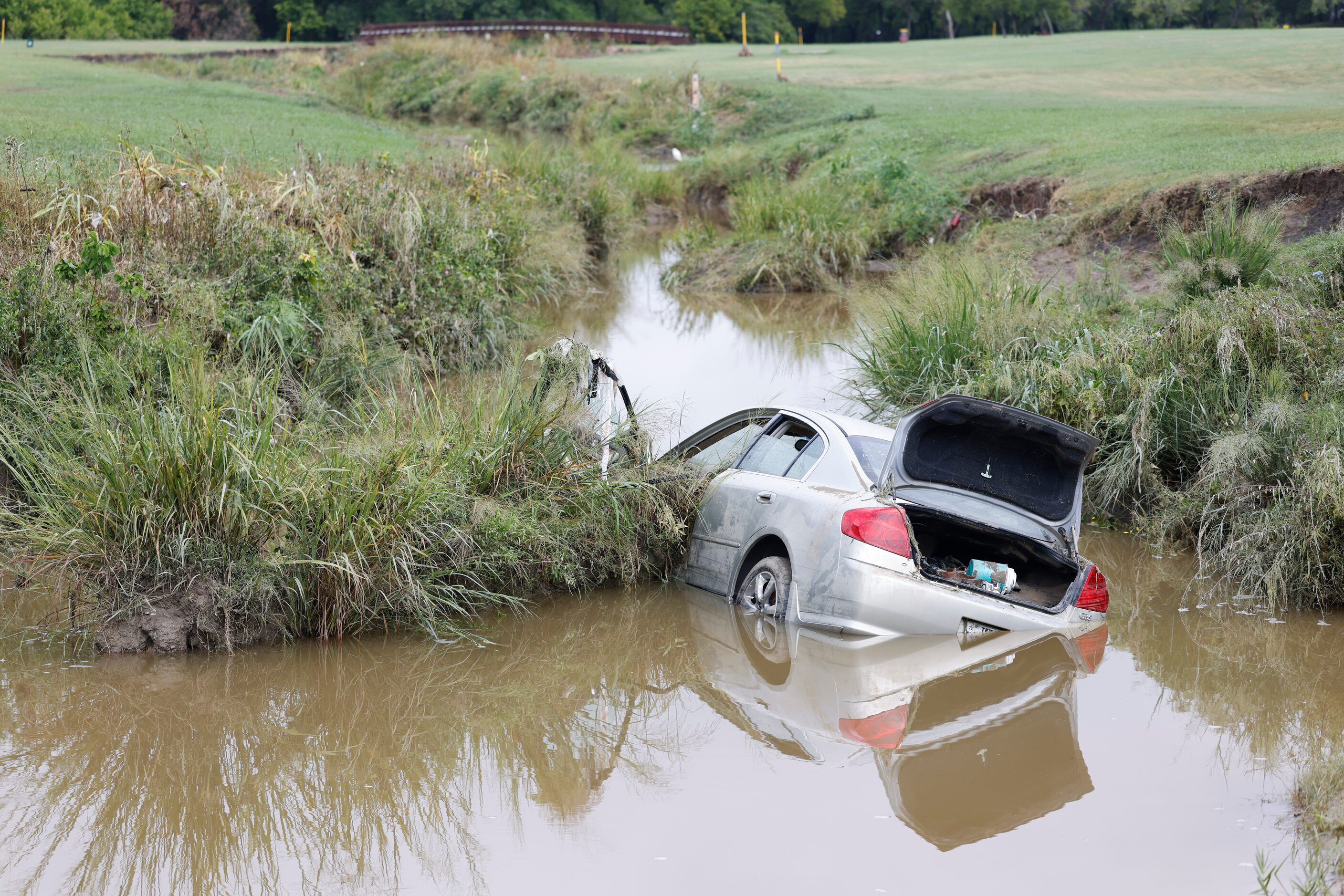 A stranded car remains on a creek at Paschall Park in Mesquite, day after Dallas-Fort Worth...