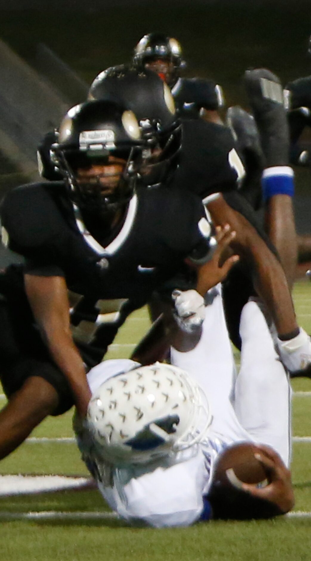 Wilmer Hutchins quarterback Andre Henderson (2) is upended by a host of Pinkston defenders...