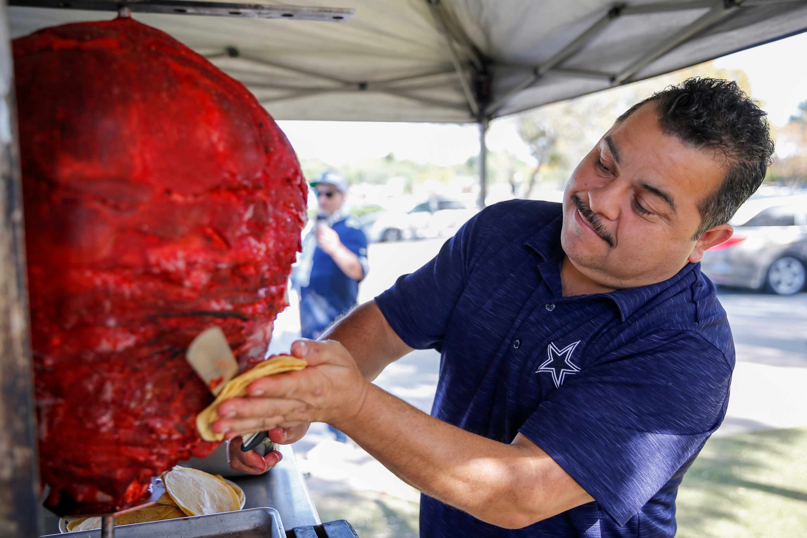 Carlos Gonzalez, 45, slices trompo for tacos before an NFL football game between the Dallas...