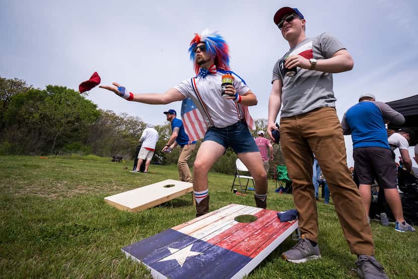 Fans Clayton Ferrell (center) and Ryan Handy play cornhole as they tailgate before the Texas...