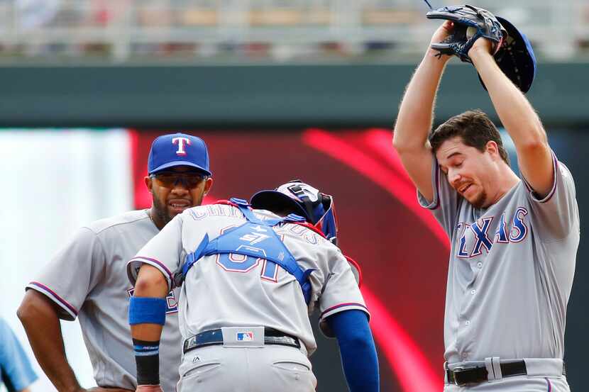 Texas Rangers pitcher Chi Chi Gonzalez wipes his brow with Rangers catcher Robinson Chirinos...