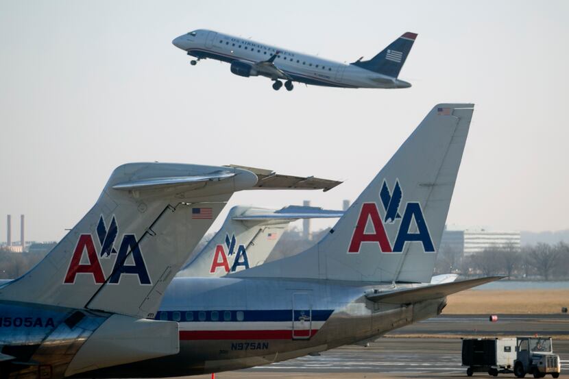 A US Airways Group Inc. airplane takes off behind AMR Corp.'s American Airlines airplanes at...