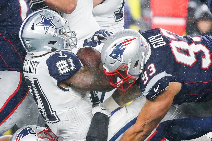 Dallas Cowboys running back Ezekiel Elliott (21) is brought down by New England Patriots...