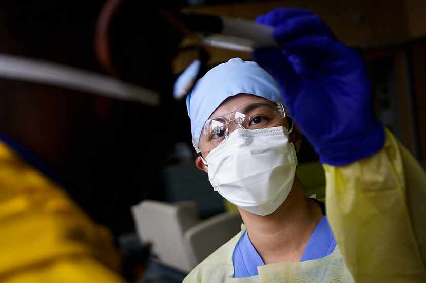 Dentist Jennifer Lo takes the temperature of a messenger as medical professionals screen...