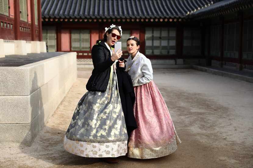 Visitors in traditional clothing take a selfie at Gyeongbokgung Palace.
