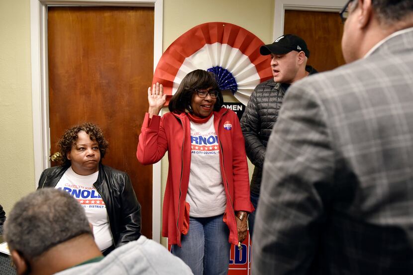 Candidate Carolyn King Arnold, center, raises her right hand as if she was being sworn in as...