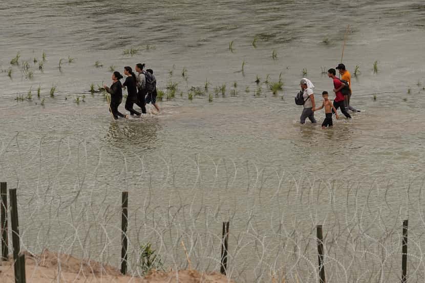 Migrants walked along concertina wire by the Rio Grande in Eagle Pass on July 12. A state...