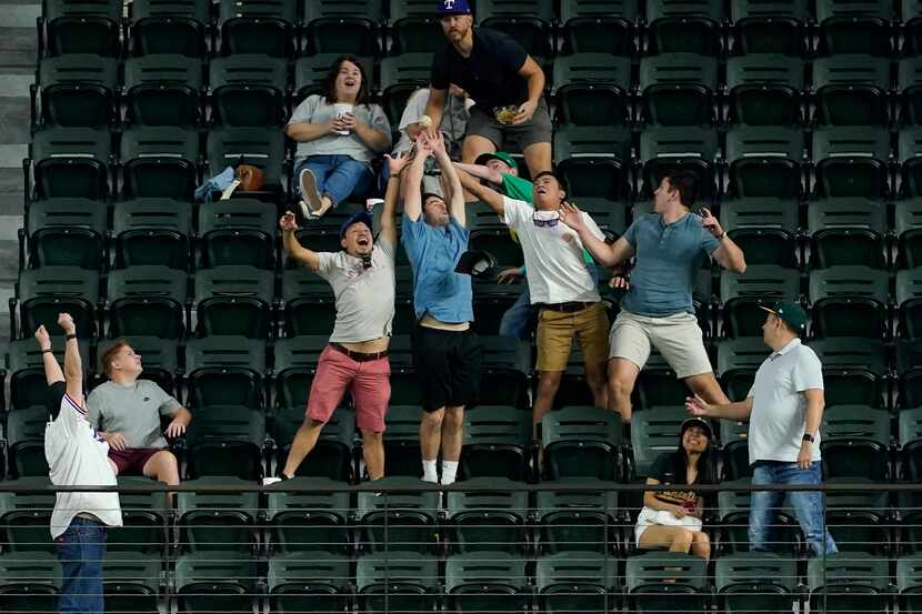 Fans compete for a three-run home run ball hit to right by Texas Rangers' Nathaniel Lowe in...