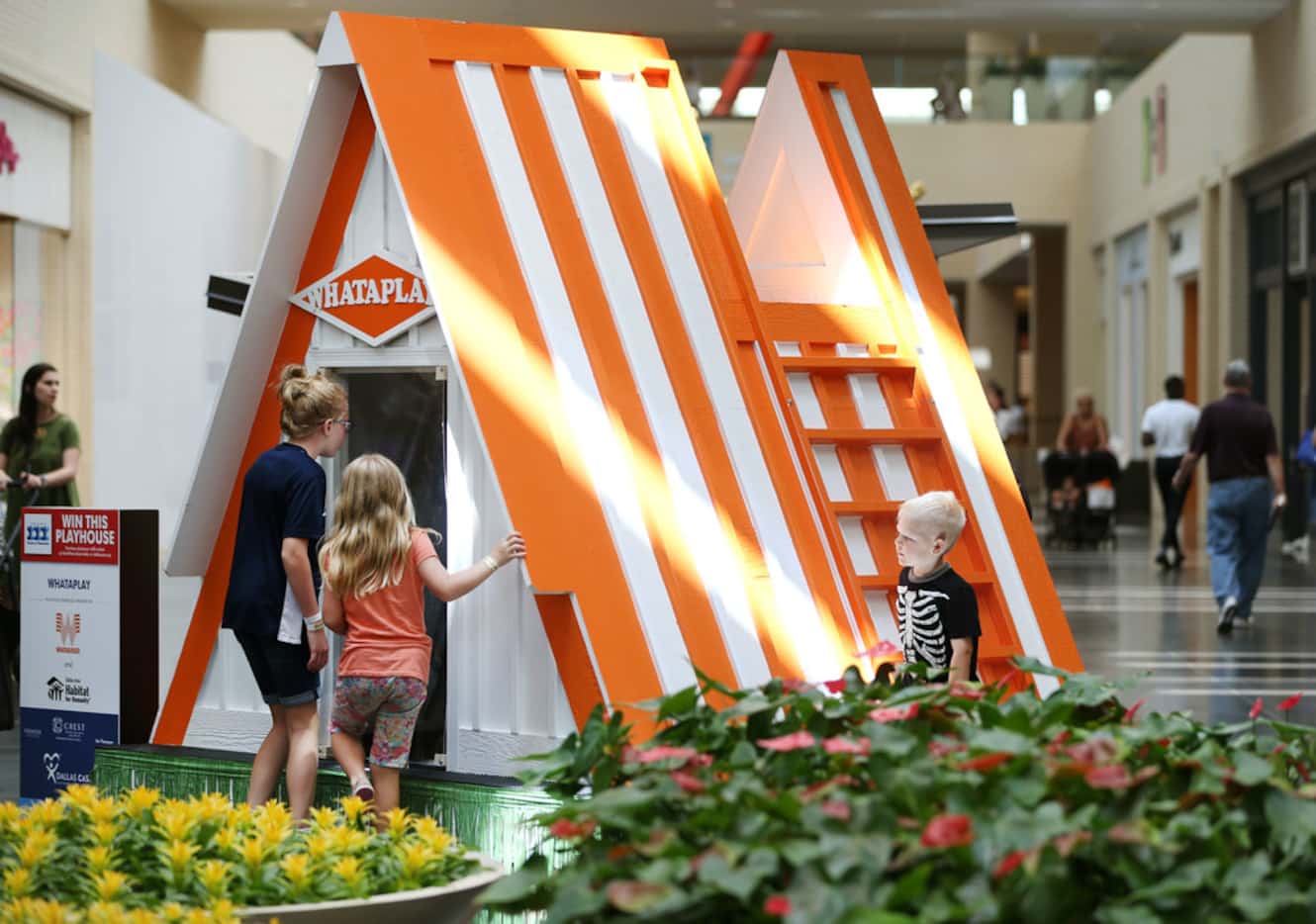 Children peer inside a playhouse on Friday that was made to look like a Whataburger and...