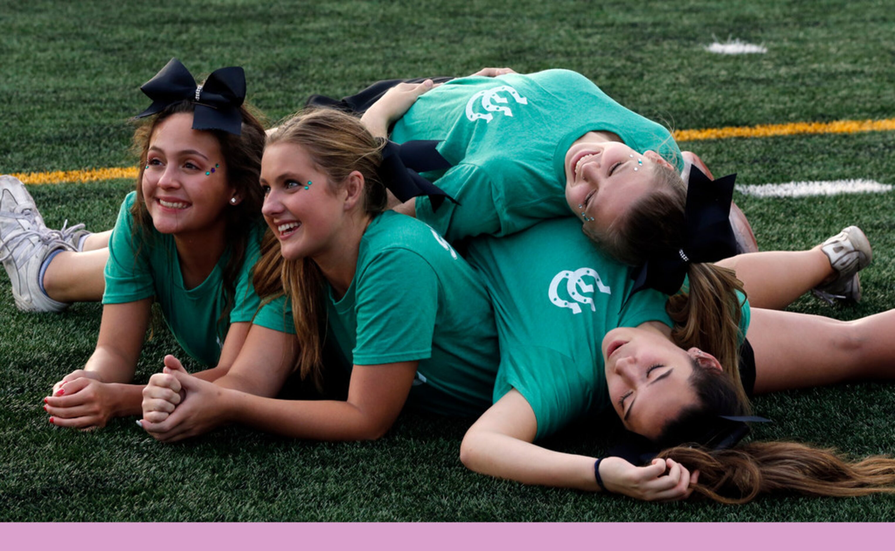 The Arlington High cheerleaders pose for a photo in a pile before the start of the team's...