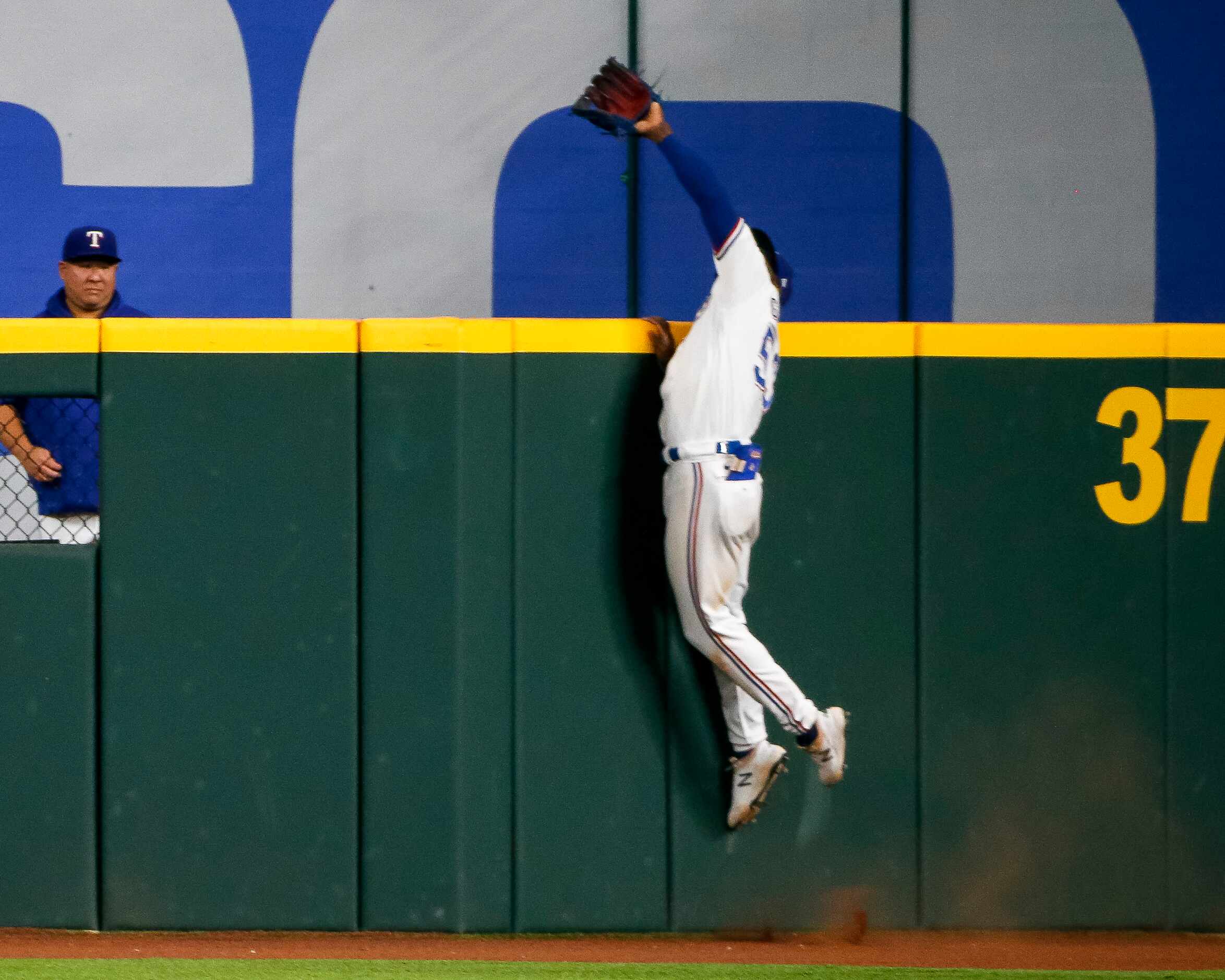 Texas Rangers right fielder Adolis Garcia (53) makes a leaping catch over the outfield wall...