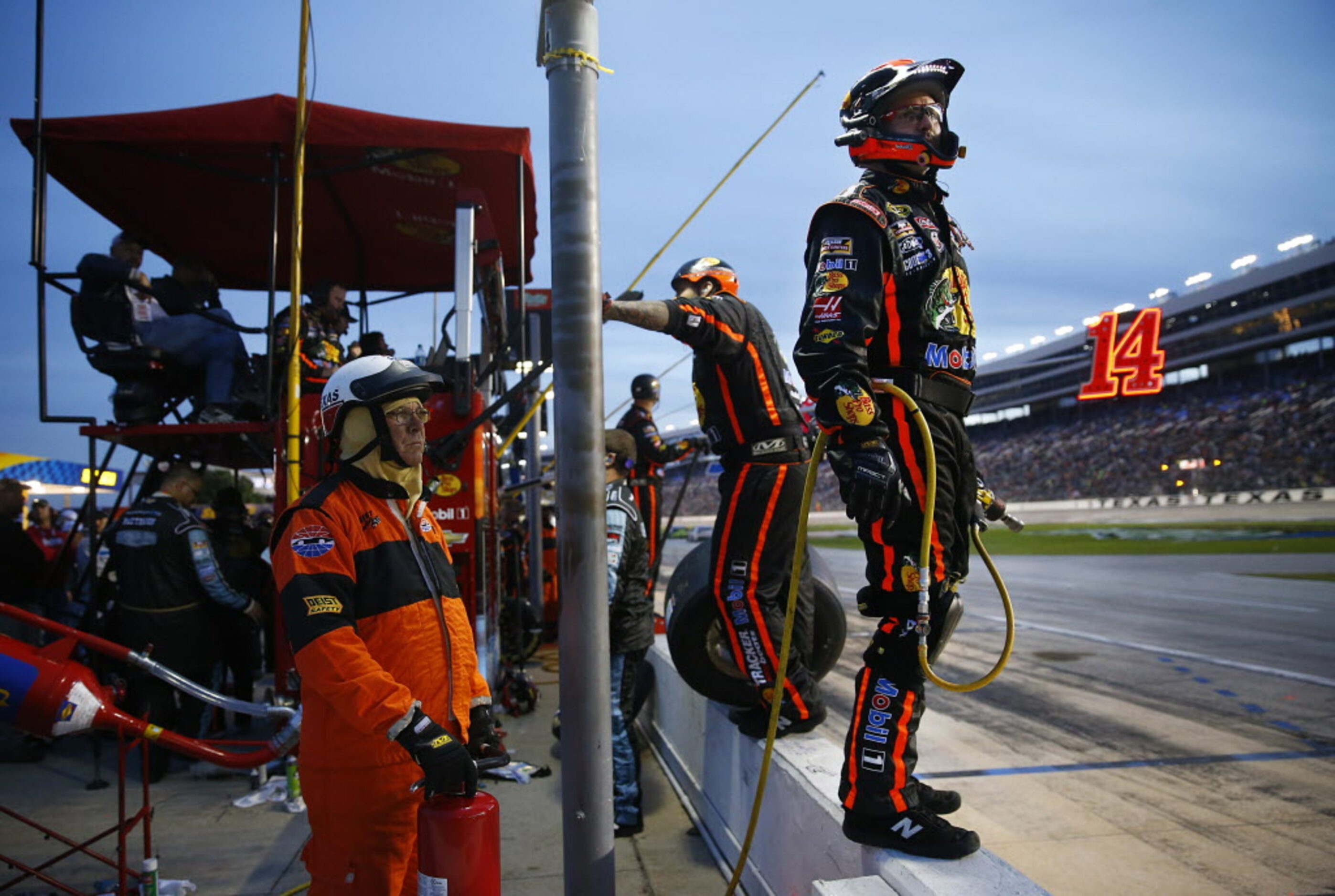 Crewman for Sprint Cup Series driver Tony Stewart (14) watch as the cars remain on the track...