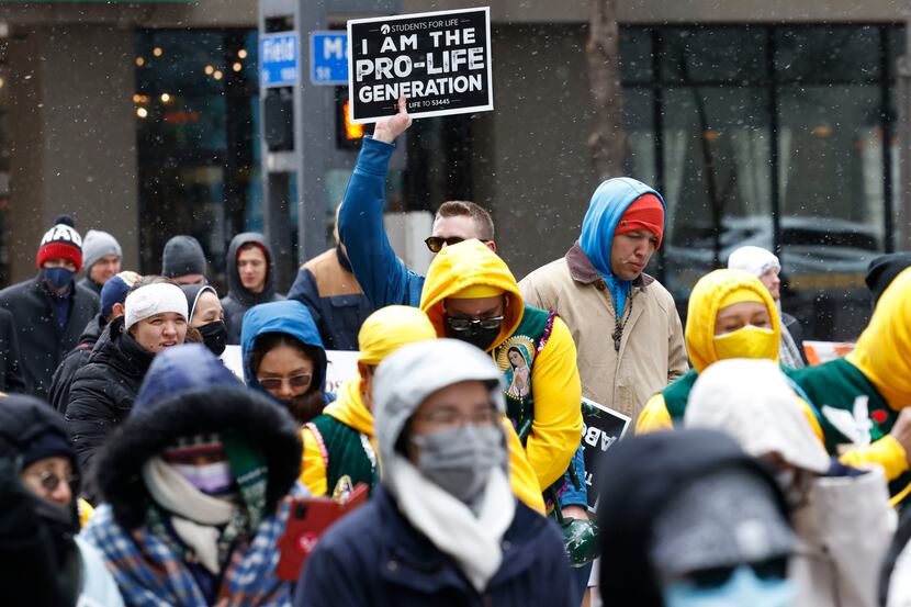 Marchers holding signs walk along Ross Ave. during the North Texas March for Life,...