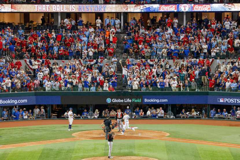 Fans celebrate as Texas Rangers first baseman Nathaniel Lowe (30) crosses home plate after...