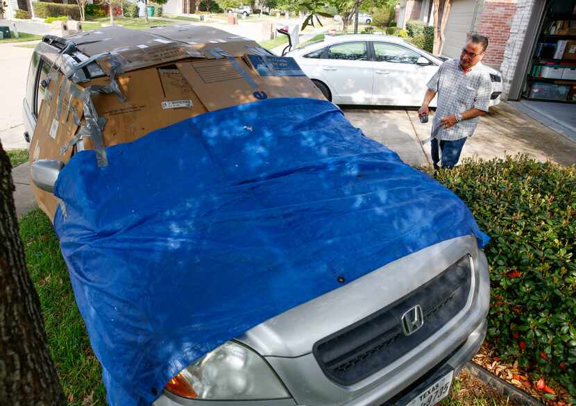 Michael Ruiz of McKinney tapes boxes and a tarp on one of his cars to protect it from hail...
