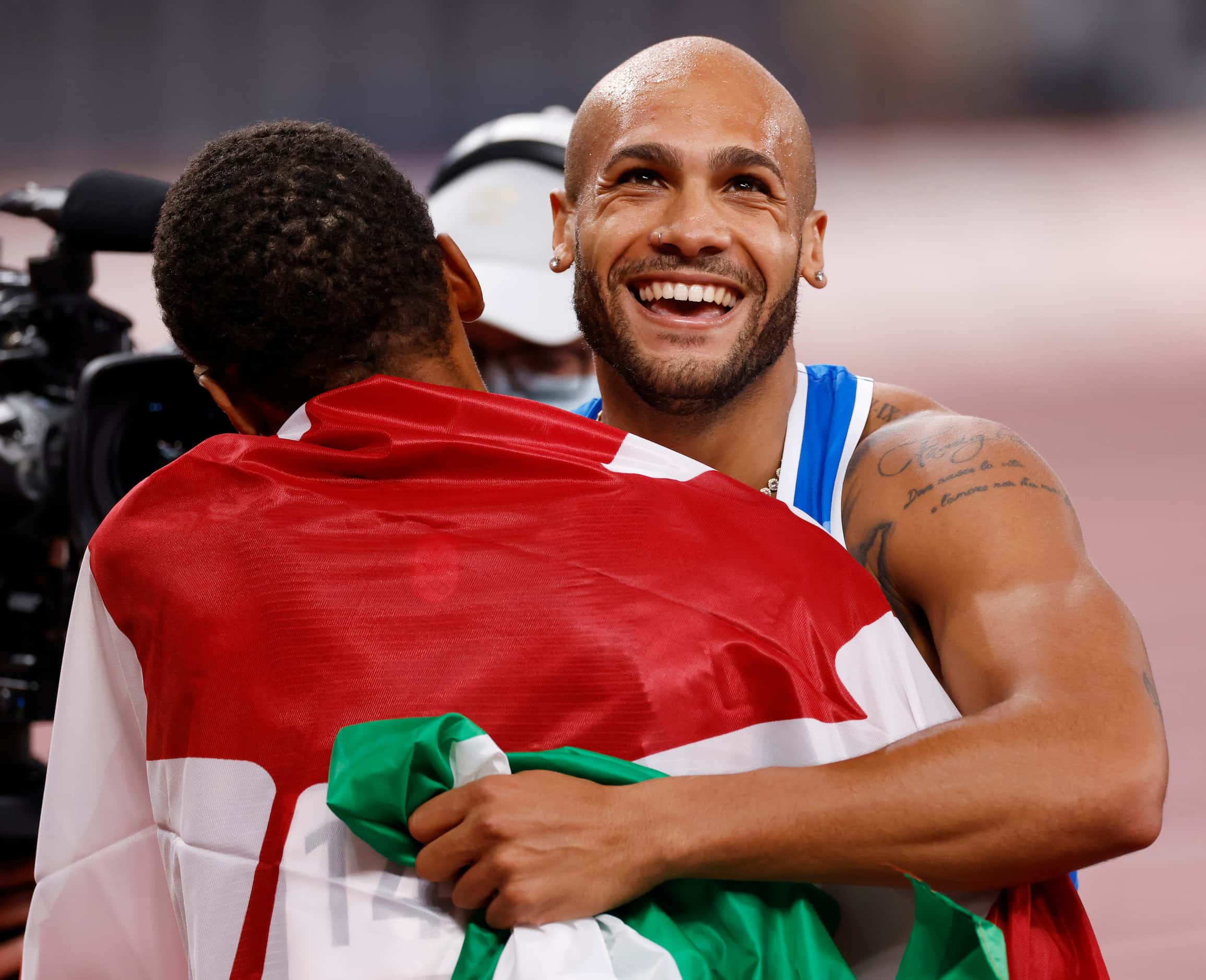 Italy’s Lamont Marcell Jacobs hugs Canada’s Andre de Grasse after competing in the men’s 100...