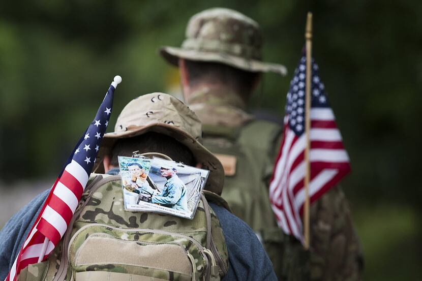 Photographs of veterans they are marching for are attached to their backpacks as  as...