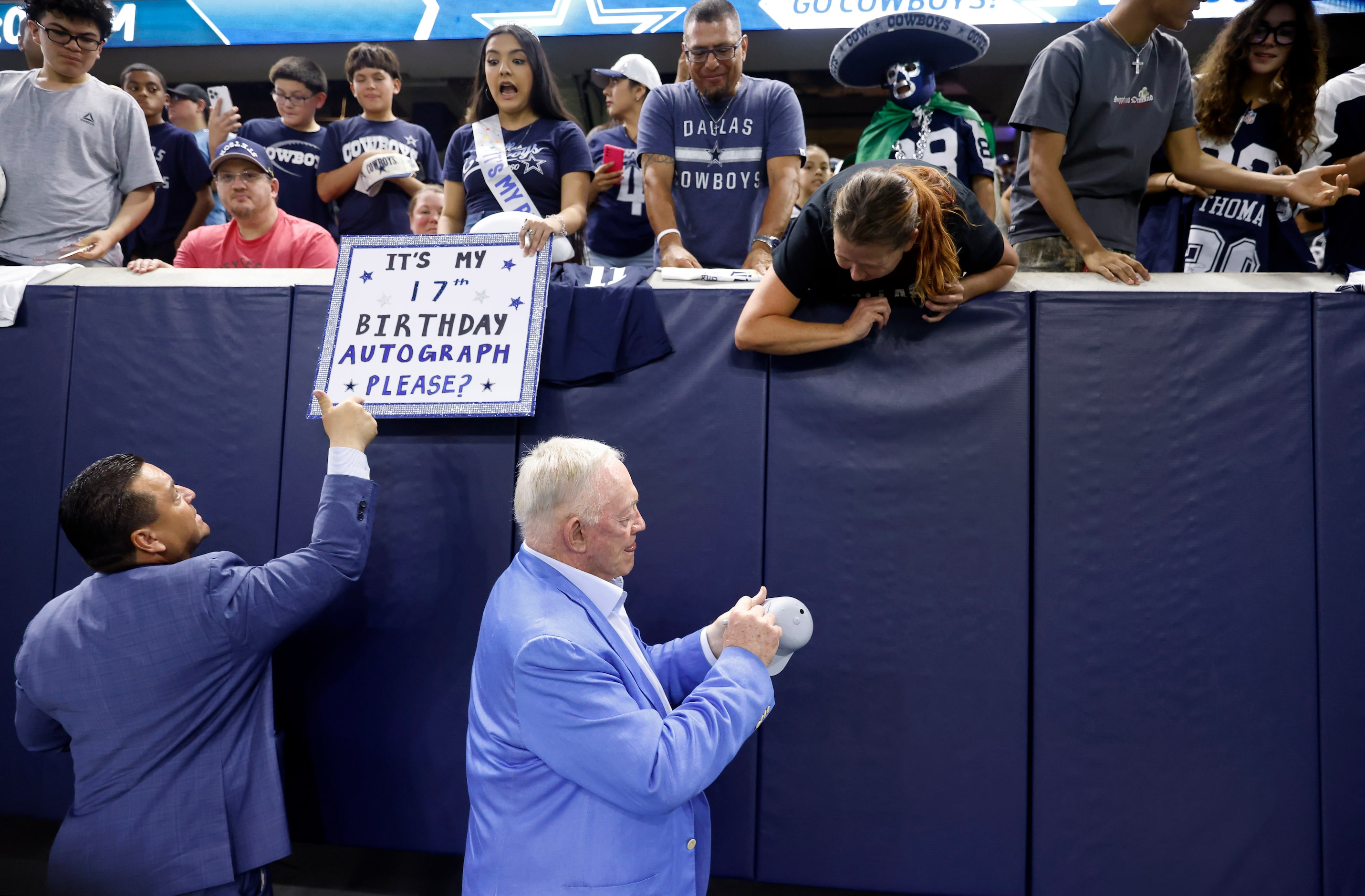 Dallas Cowboys owner Jerry Jones (right) signs autographs for fans before a Season Kickoff...