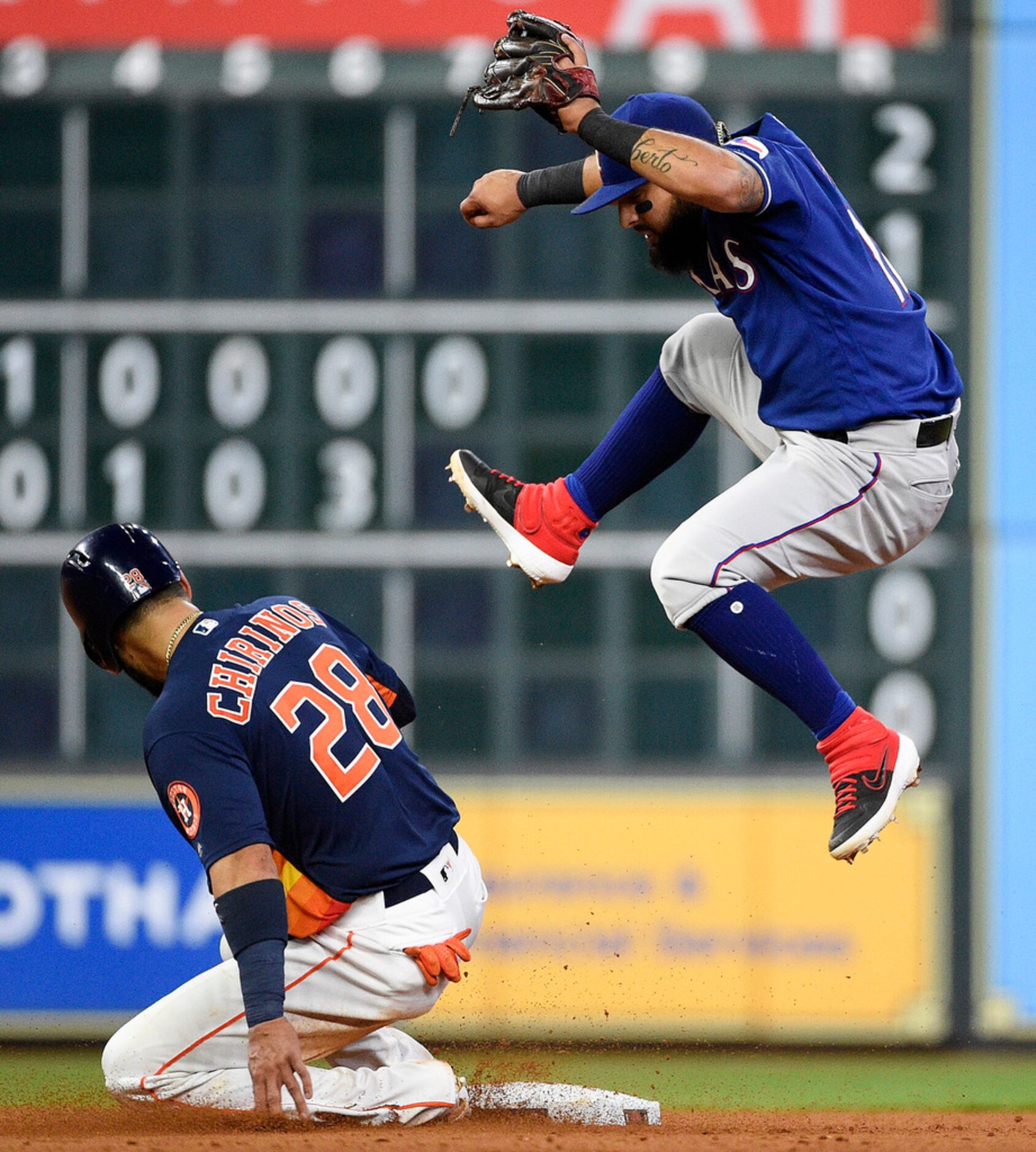 Texas Rangers second baseman Rougned Odor, right, leaps after missing the throw by relief...