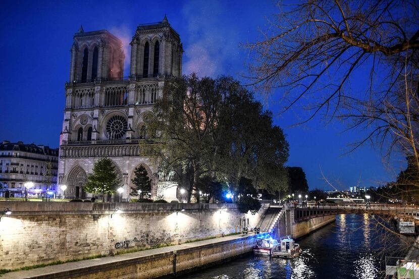 Firefighters work from a quay of the River Seine at the base of the Notre Dame de Paris...