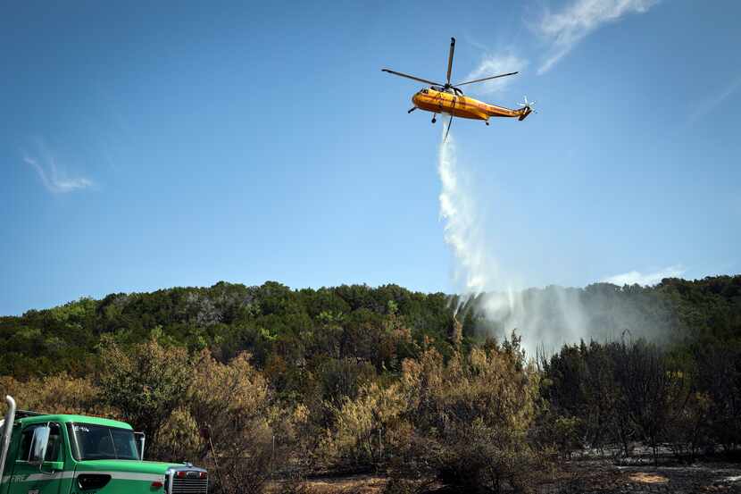 A Type 1 Helicopter drops lake water on a blaze along FM 1148 Tuesday, July 19, 2022, near...
