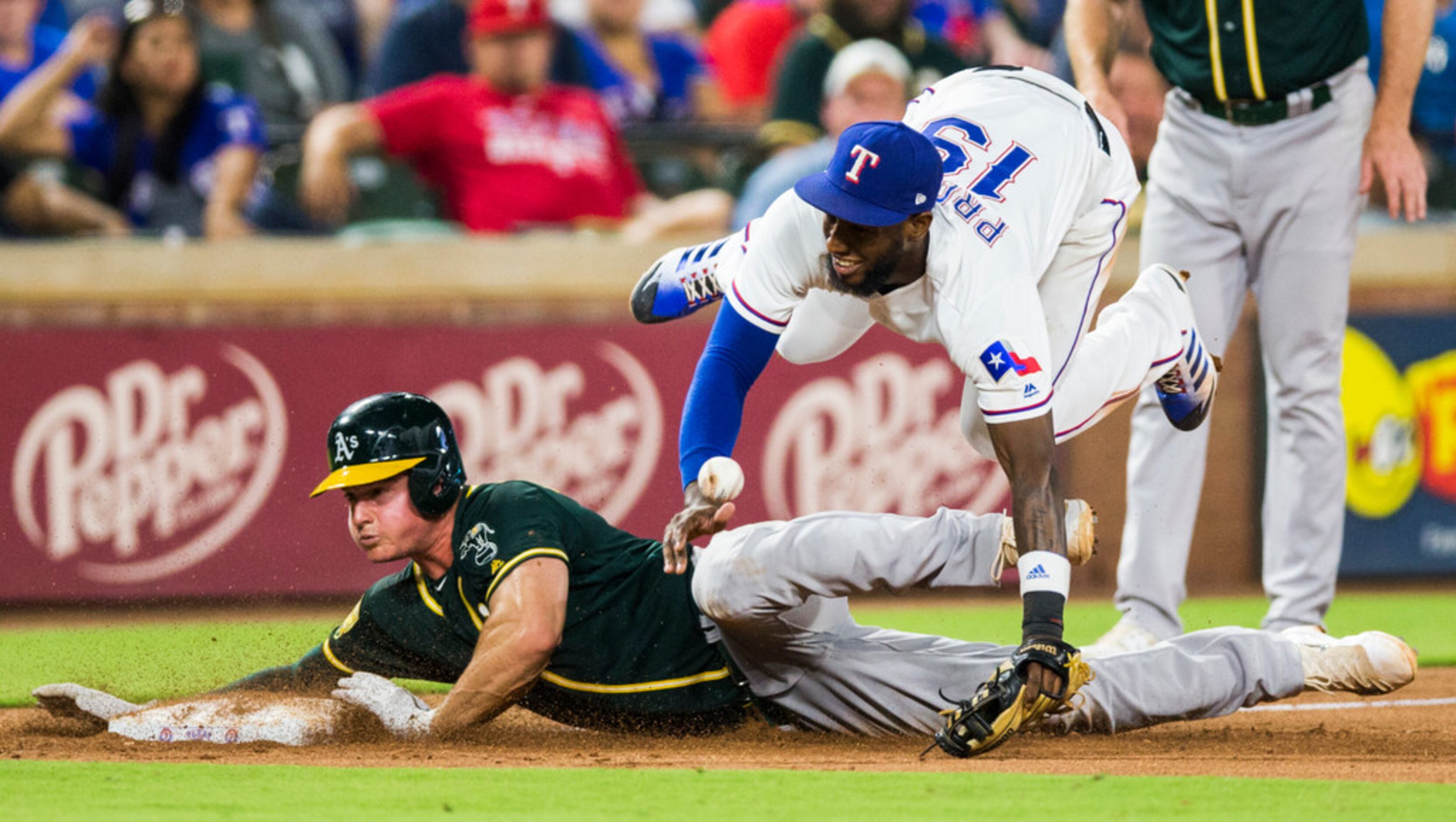 Texas Rangers third baseman Jurickson Profar (19) is tripped up by Oakland Athletics third...