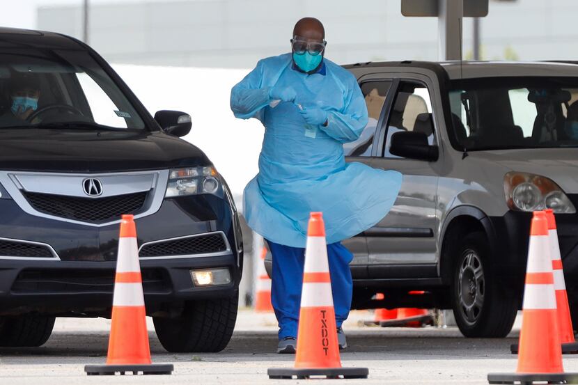 A healthcare worker collects a sample for a COVID-19 test at a drive-through testing site in...