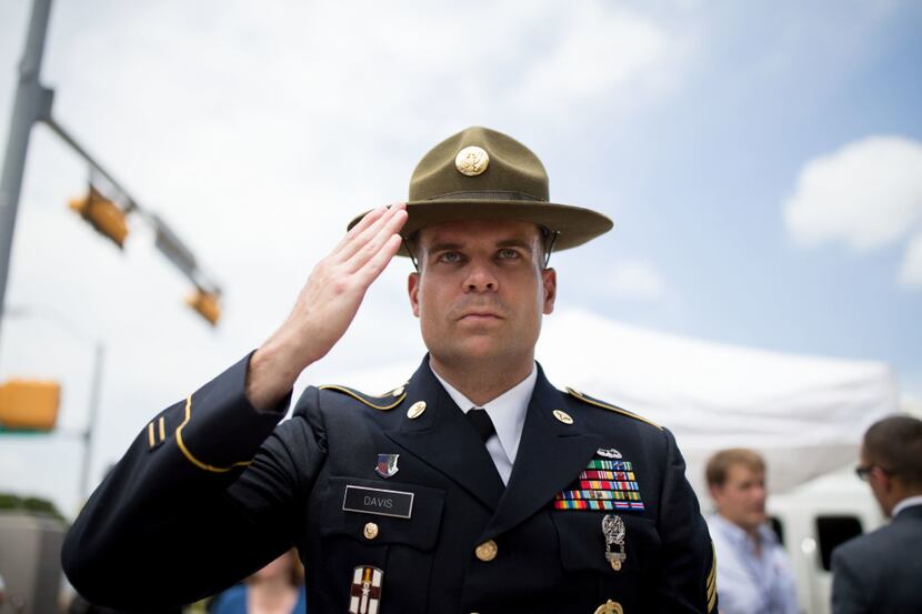 Retired Army combat medic Chandler Davis stood saluting the memorial for slain Dallas police...