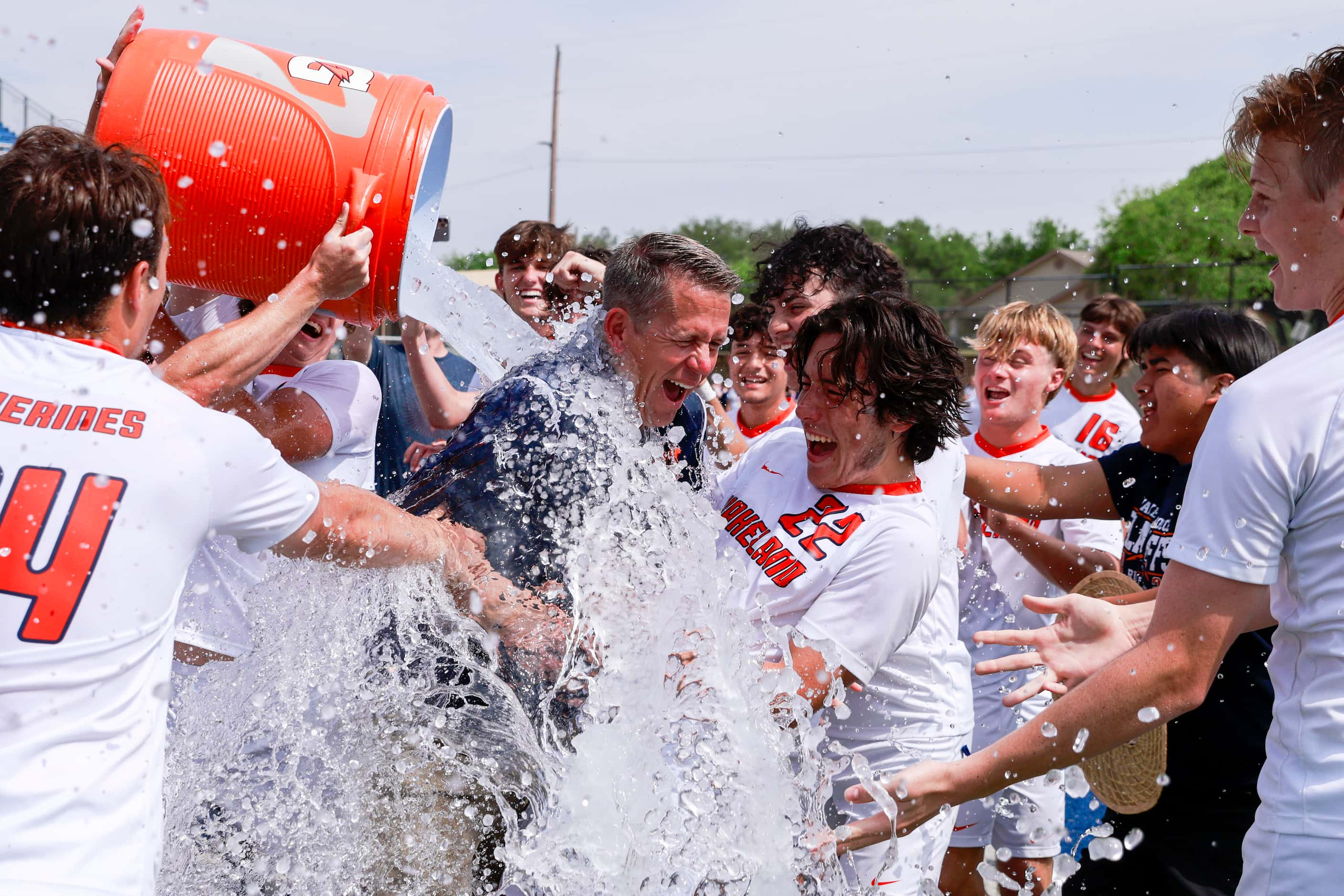 Frisco Wakeland players dump water on head coach Andy Holt alongside Frisco Wakeland forward...