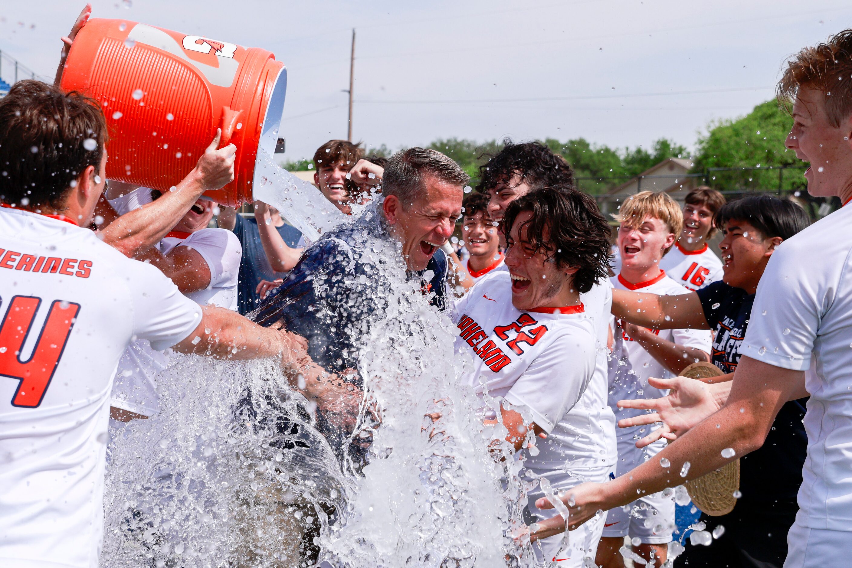 Frisco Wakeland players dump water on head coach Andy Holt alongside Frisco Wakeland forward...