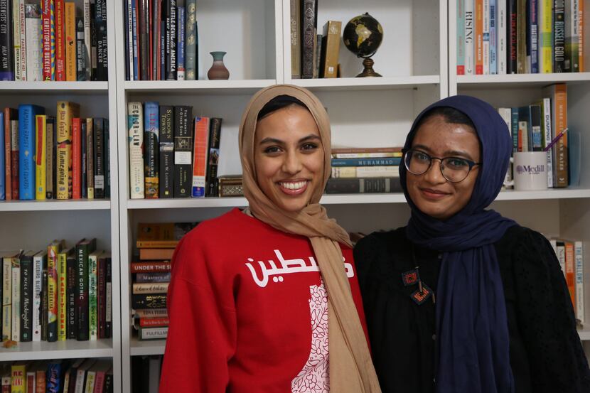 Amal and Manal Ahmed pose in front of a bookcase.