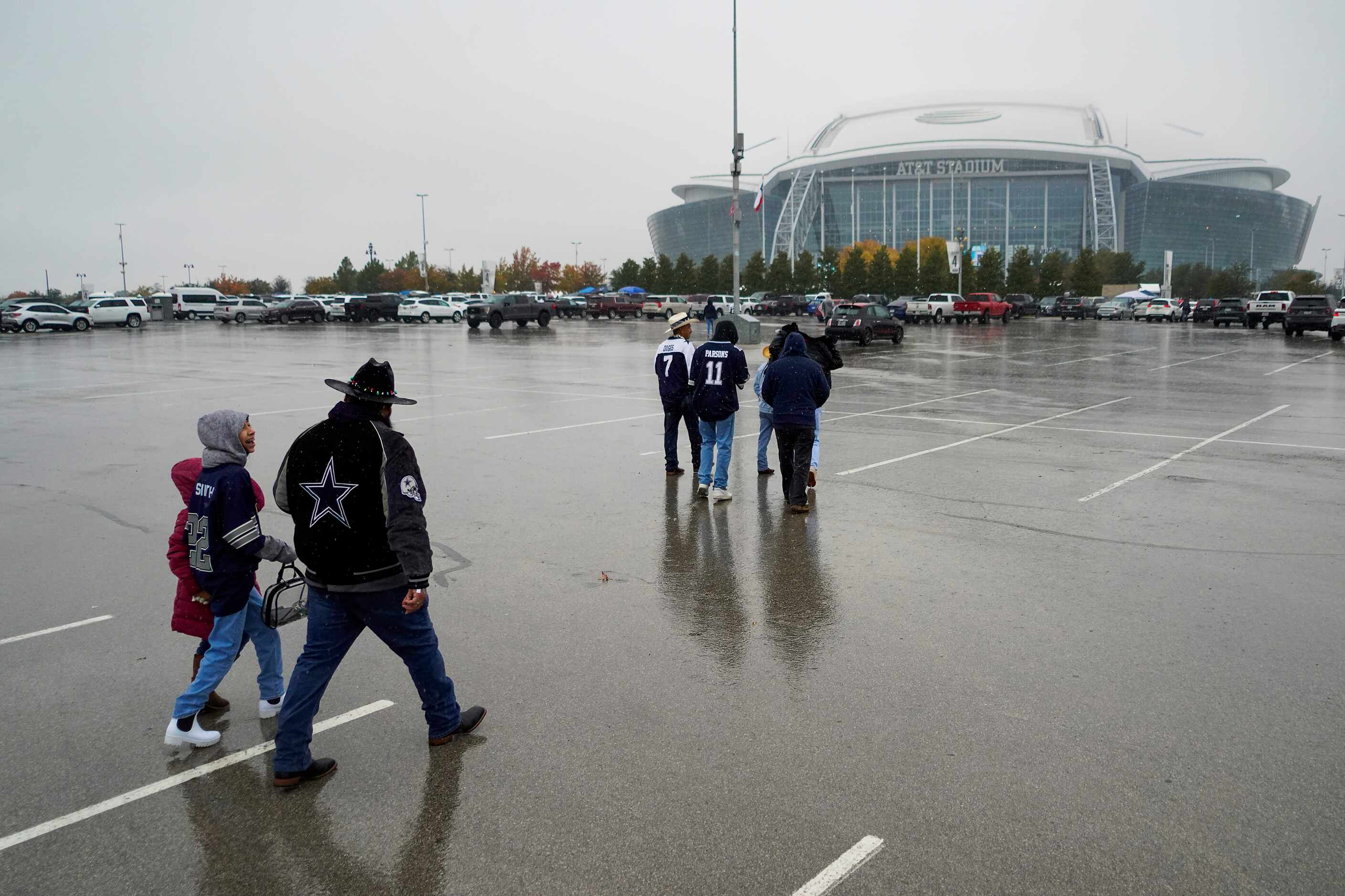 Fans head to the stadium in the rain before an NFL football game between the Dallas Cowboys...