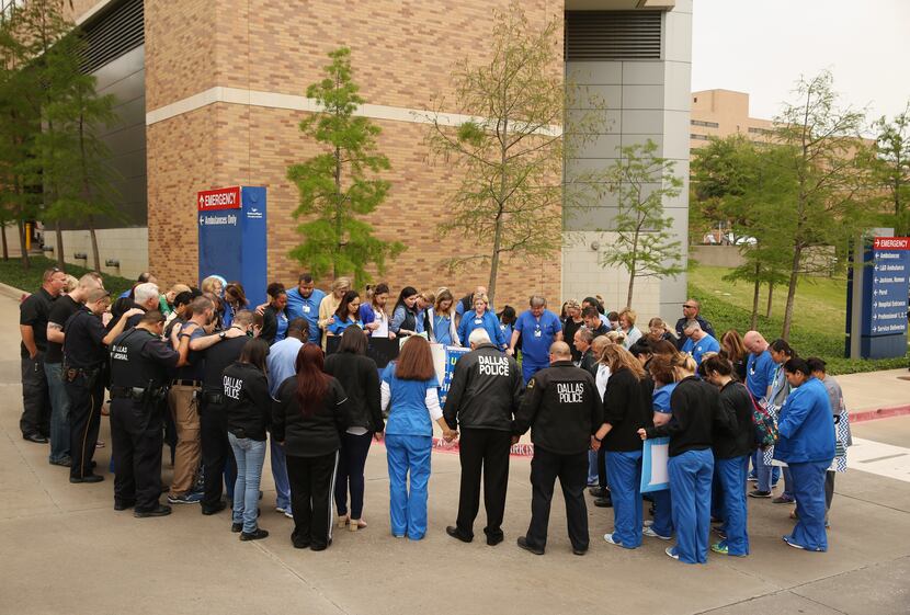 Members of the Dallas Police Department and hospital personnel pray outside Texas Health...