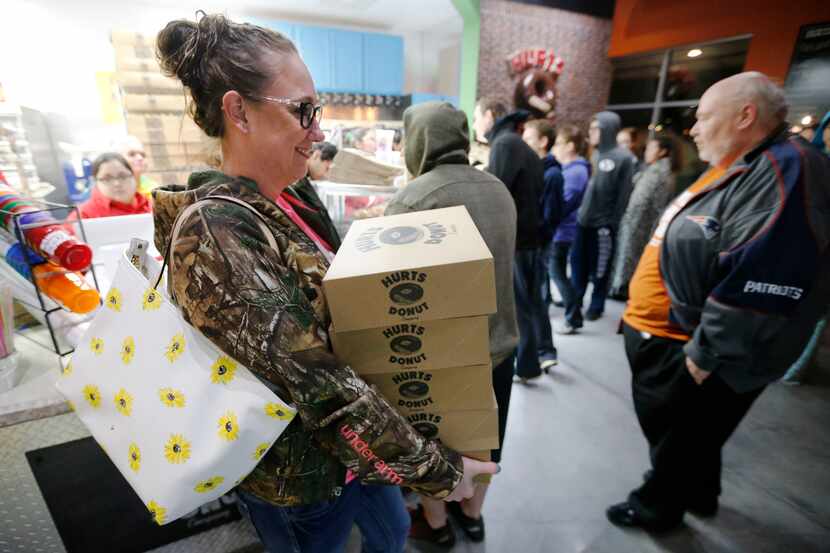 Nicole Bazhaw of Garland carries out 5 dozen donuts after being the first to purchase Hurt's...