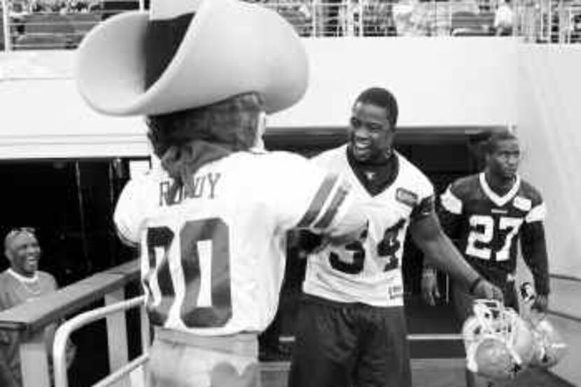 Cowboy Deon Anderson got stopped on his way to the field by team mascot Rowdy on Tuesday...
