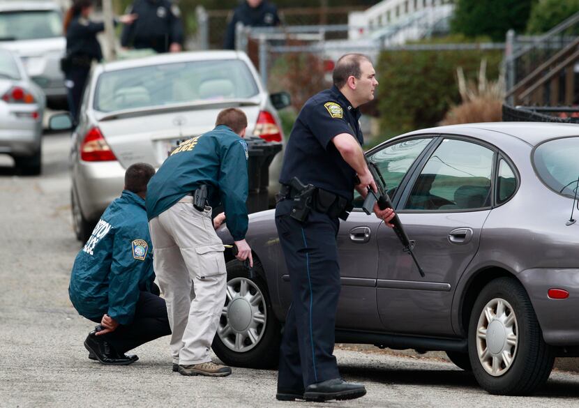 Police officers take up positions Friday morning outside a home in Watertown, Mass., during...