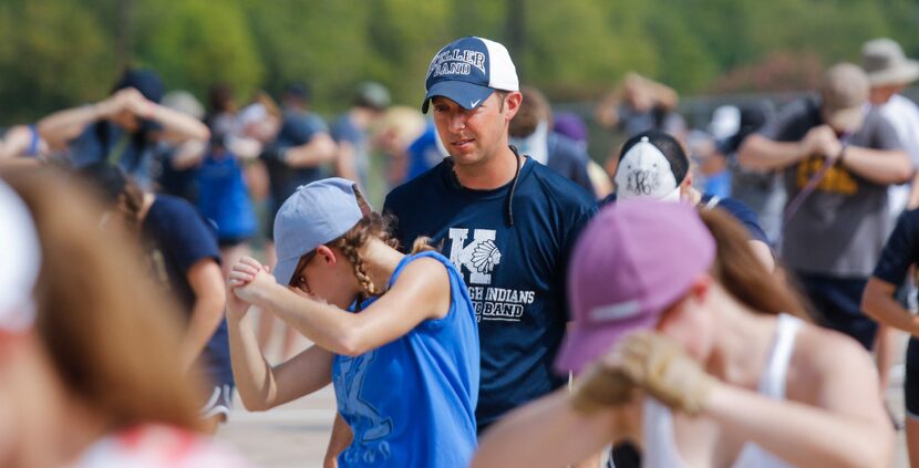 Keller High assistant band director Ryan Heath (center) looks over the posture of band...