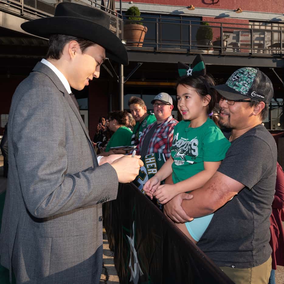 Dallas Stars player Jason Robertson, left, signs his autograph while meeting fans Rosalyn...