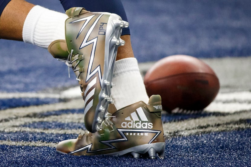 Dallas Cowboys quarterback Dak Prescott weats cleats honoring US veterans as he warms up...