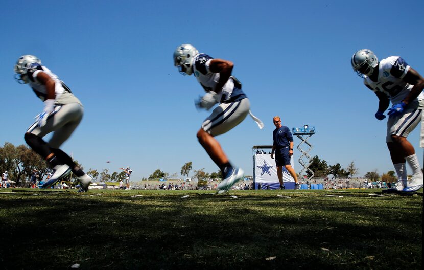 Dallas Cowboys head coach Jason Garrett (in background) watches as his offensive players...