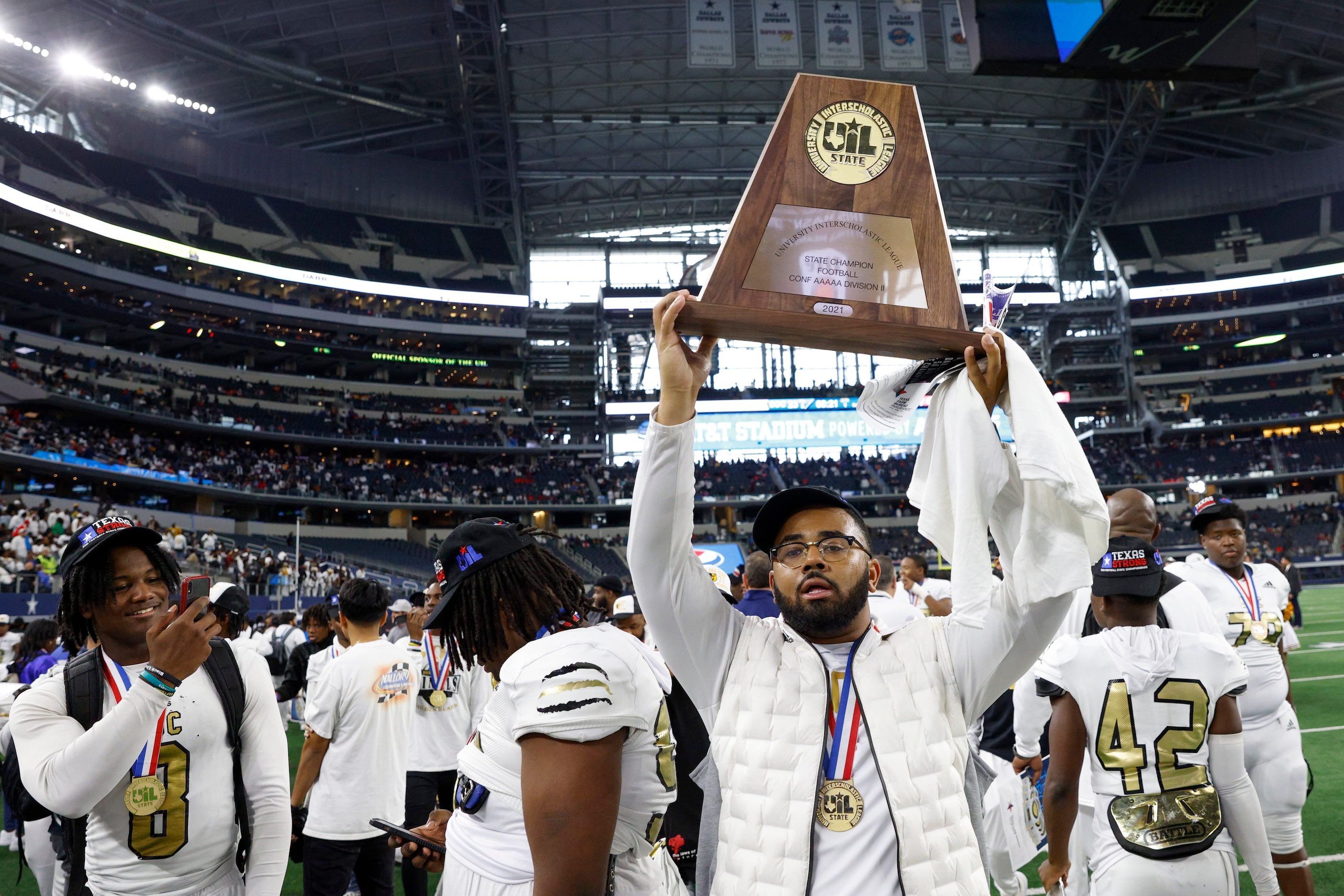 South Oak Cliff assistant coach Domenic Spencer raises the championship trophy after the...