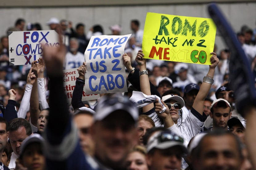 Fans hold signs supporting Tony Romo's bye-week trip to Mexico during the Cowboys'...