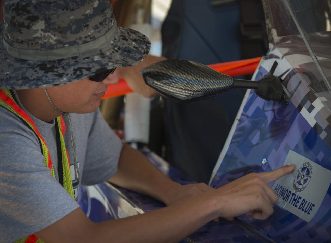 Aidan Russo, a senior at Byron Nelson High School puts an Honor The Blue sticker on his...