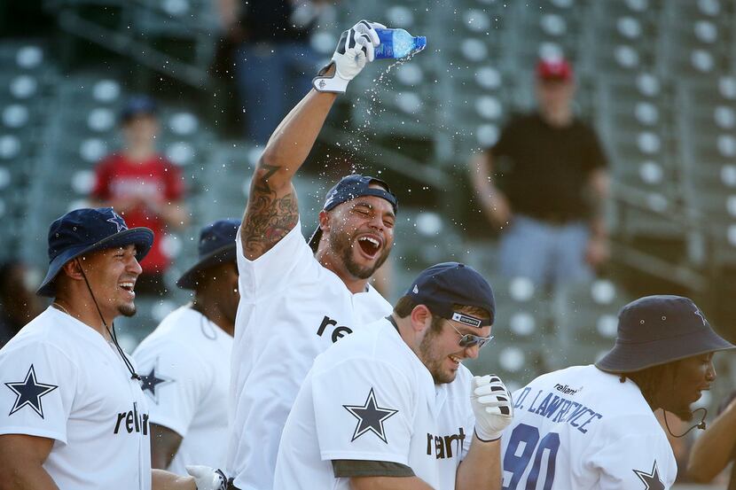 Dallas Cowboys quarterback Dak Prescott throws water on guard Zack Martin at the end of the...