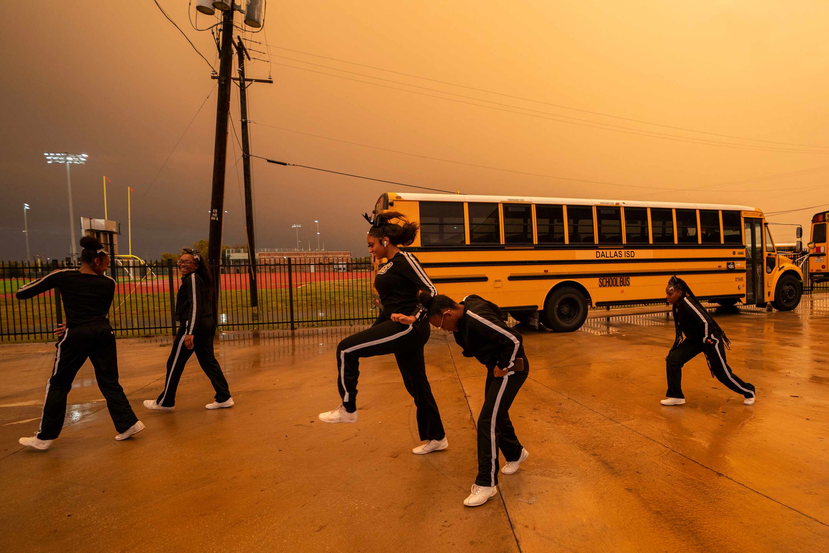 Members of the South Oak Cliff dance team leap over flowing water during a lightning delay...