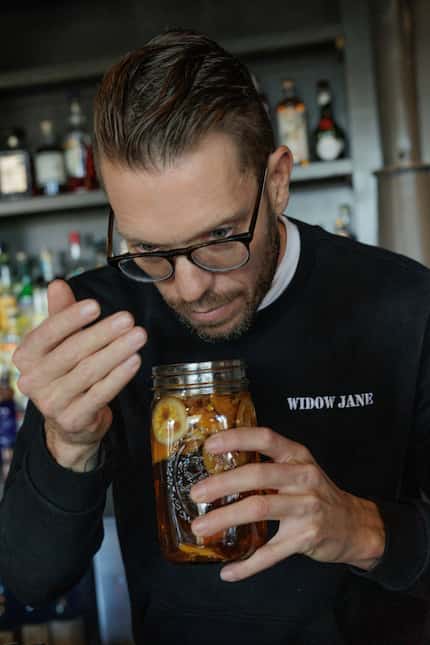 Alex Fletcher smells a concoction of bitters to see if they are ready for use at Henry's...