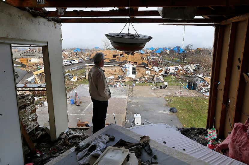 From the second floor of a neighbor's damaged home, Gary Hale looks out at the lot where his...