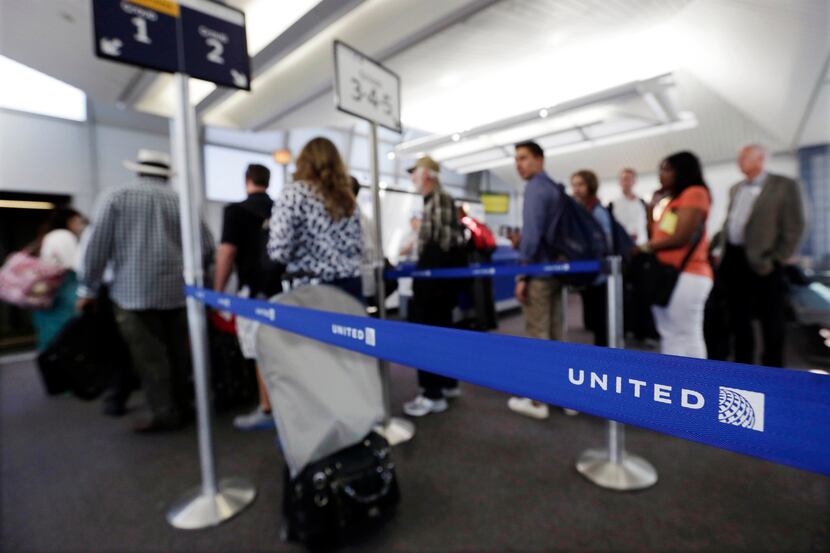 FILE - In this May 8, 2013, file photo, groups of passengers wait at a United Airlines gate...