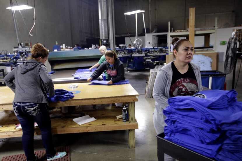 Workers produce NCAA championship t-shirts through the night at Pony Xpress Printing in...